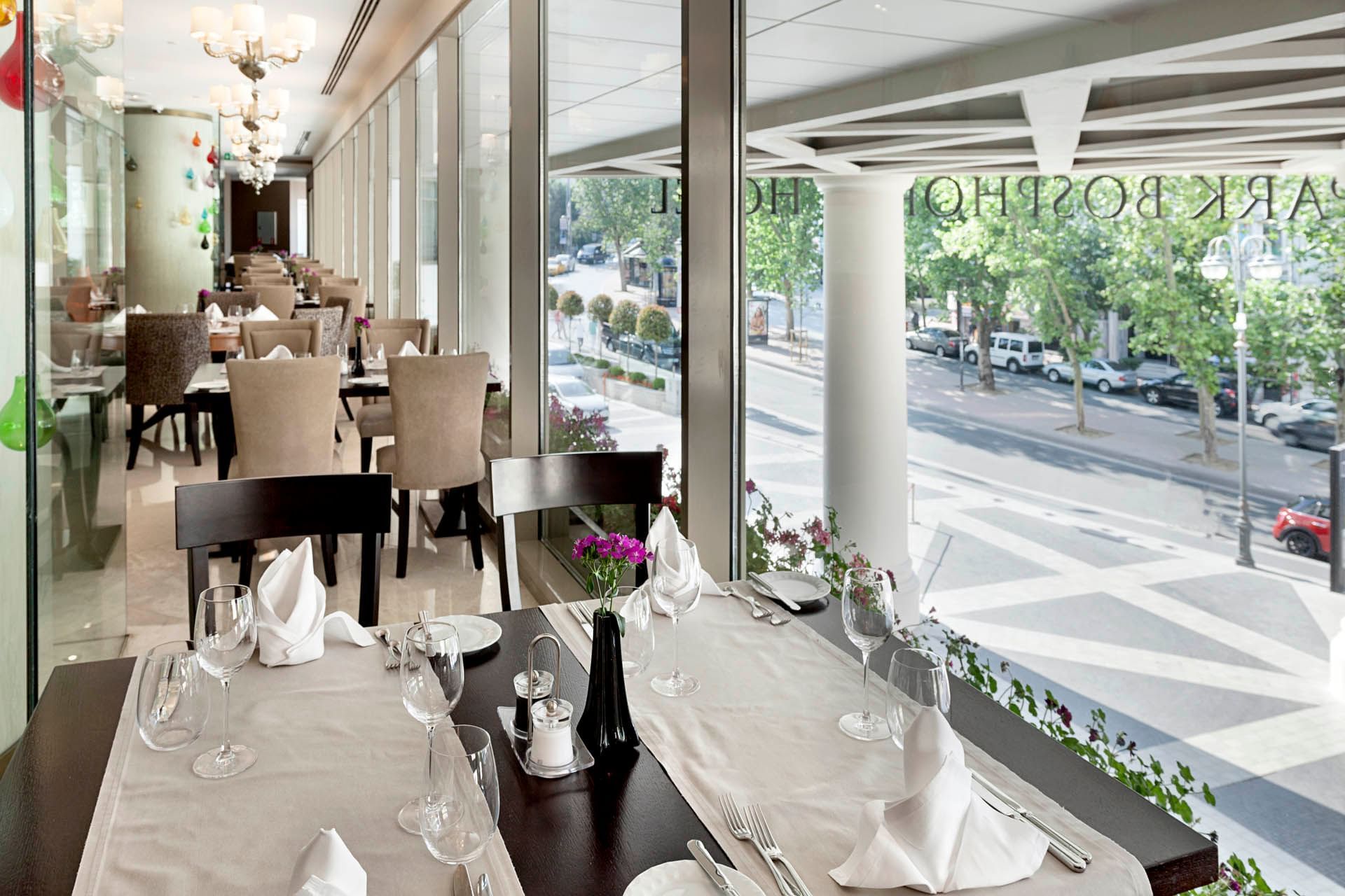 Evergreen Area dining space with wooden tables and chairs, surrounded by lush green at CVK Park Bosphorus Hotel Istanbul