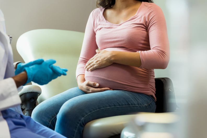 A doctor wears protective gloves as she prepares to examine an adult pregnant woman.